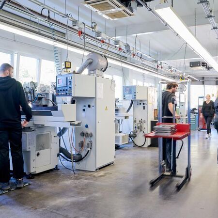 Innenansicht einer modernen Fertigungshalle mit Maschinen und Mitarbeitern