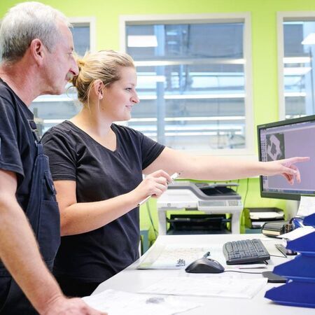 Two colleagues collaborating at a computer in a modern office