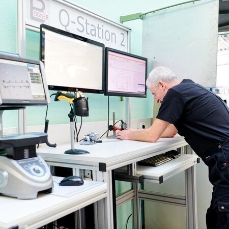 Technician working at a quality control workstation with monitors and equipment