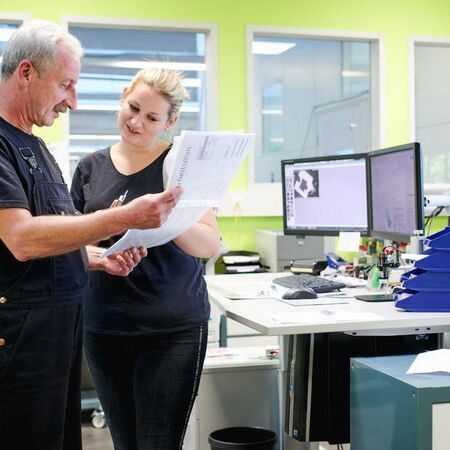 Two colleagues discussing documents in an office environment