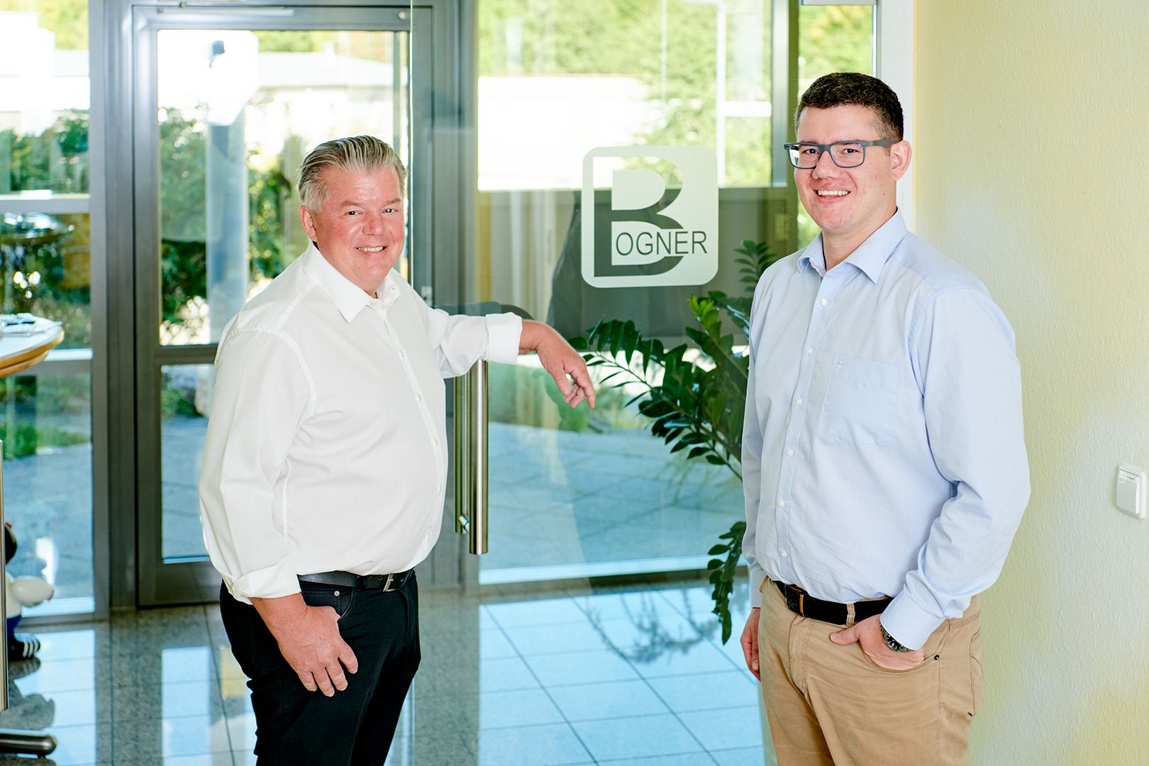 Two business partners smiling in front of the Bogner office entrance